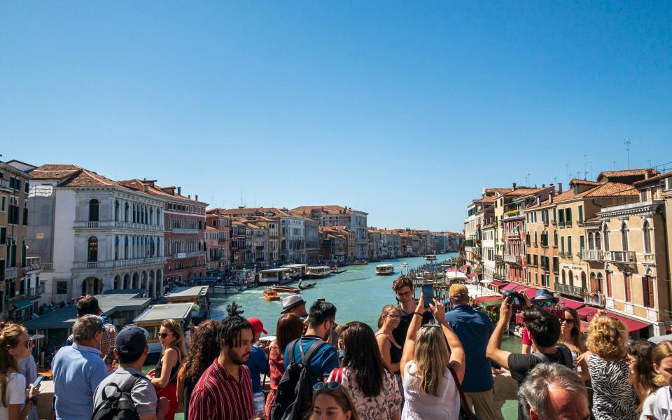 Rialto Bridge overlooking the Grand Canal with crowds of tourists in Venice, Italy