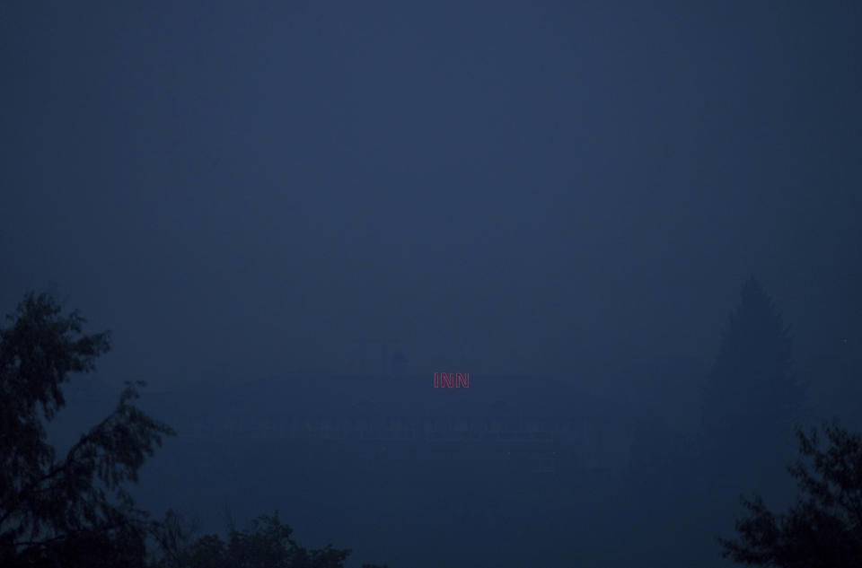A neon sign on the roof of a hotel is seen through thick wildfire smoke east of Kamloops, British Columbia, on Sunday, Aug. 20, 2023. (Darryl Dyck/The Canadian Press via AP)