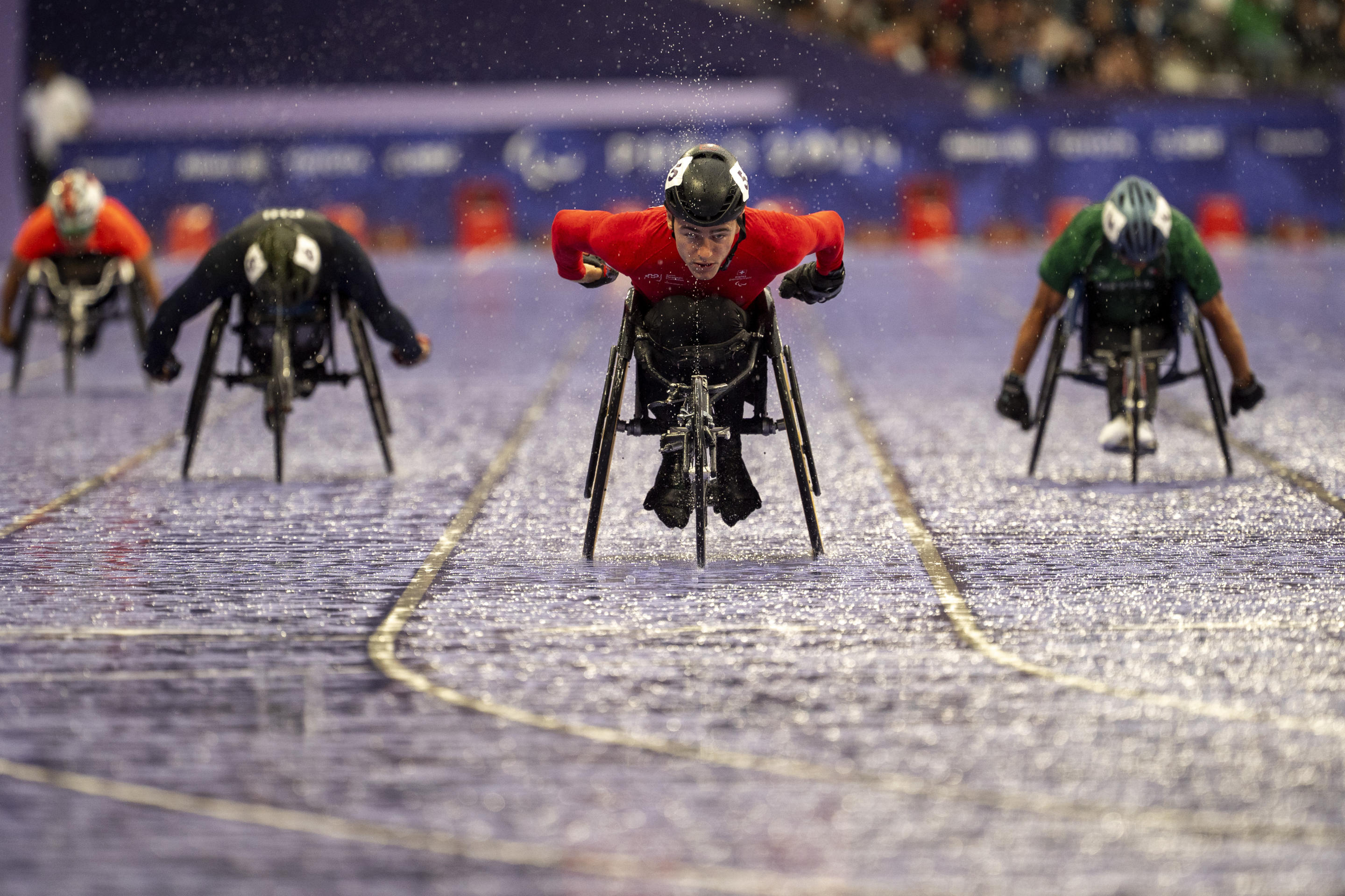 Wheelchair participants race on a track.