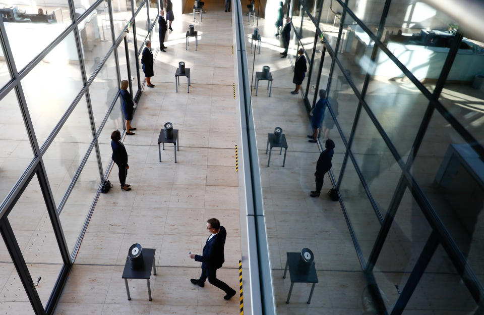 Delegates cast their votes, during a session of the lower house of German parliament, Bundestag, on the outbreak of the coronavirus disease (COVID-19) in Berlin, Germany, March 25, 2020. REUTERS/Michele Tantussi