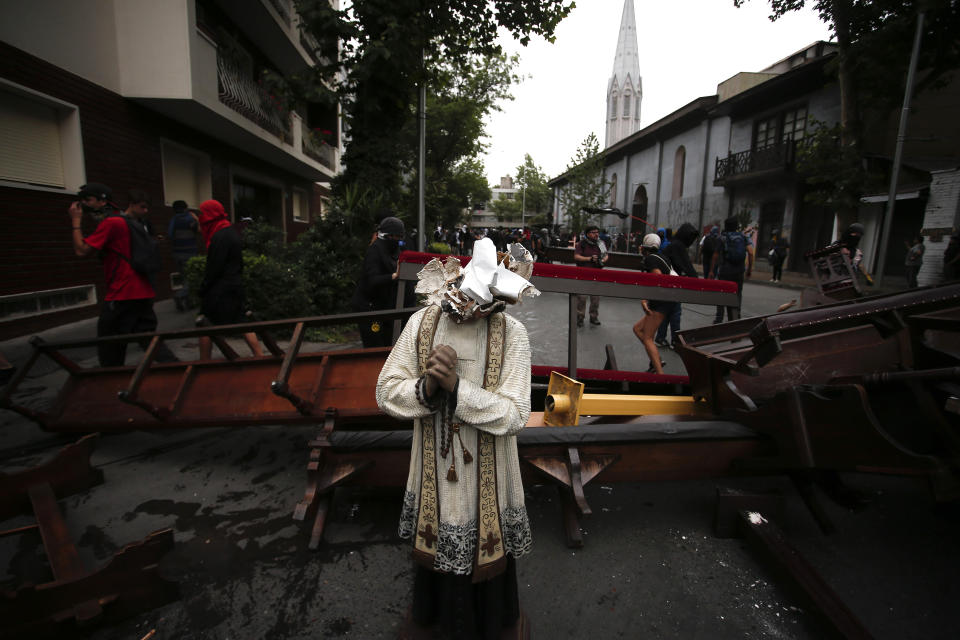 A damaged statue taken from a church forms part of barricade created by anti-government protesters, in Santiago, Chile, Friday, Nov. 8, 2019. Chile's president on Thursday announced measures to increase security and toughen sanctions for vandalism following three weeks of protests that have left at least 20 dead. (AP Photo/Luis Hidalgo)