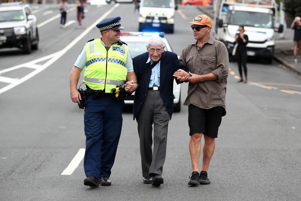 John Sato, 95, is helped down the street at an anti-racism rally in Auckland, New Zealand, on March 24, following the Christchurch massacre