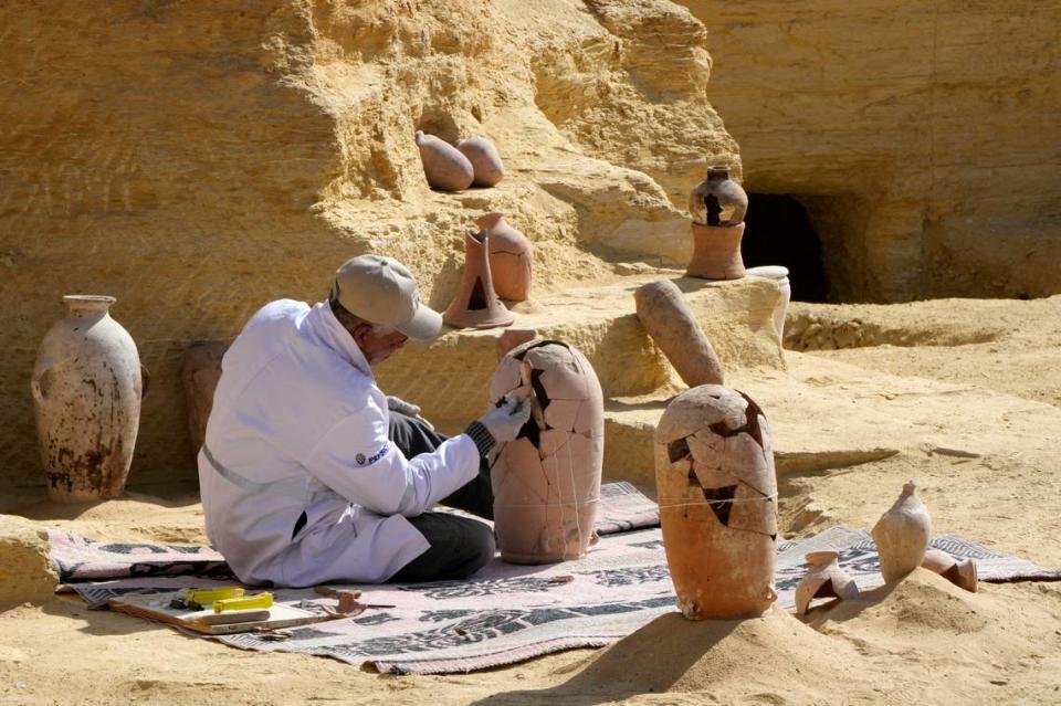 Un arqueólogo egipcio restaura una cerámica recientemente descubierta en el yacimiento de una necrópolis. (AP Photo/Amr Nabil)