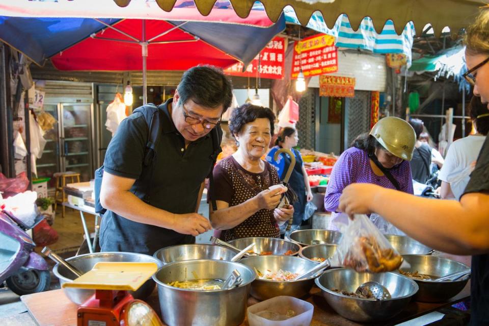 王浩一湊身在一群婆婆媽媽當中，在鹿港菜市仔覓食。