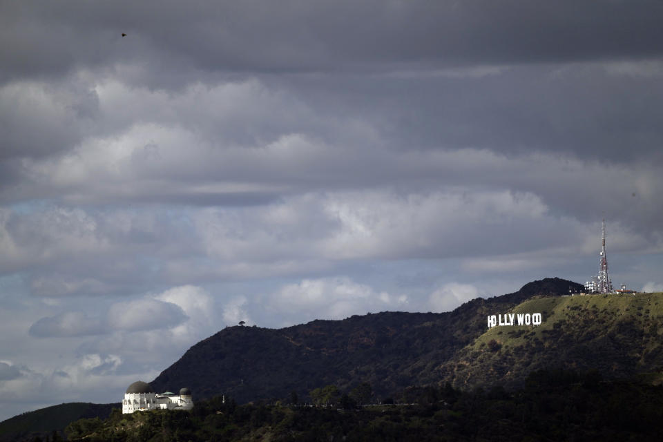 Heavy clouds move over the Griffith Observatory, left and the Hollywood Sign in this view from Los Angeles, Thursday, Feb. 8, 2024. Skies cleared over most of California on Thursday after days of wind, rain and heavy snowfall that caused power outages, street flooding and damaging mudslides. (AP Photo/Damian Dovarganes)