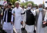 Pakistan's President Arif Alvi, second right, Foreign Minister Shah Mahmood Qureshi, third right, and parliamentarians attend a rally to show solidarity with the Kashmiri people on the eve of the first anniversary of India's decision to revoke the disputed region's semi-autonomy, in Islamabad, Pakistan, Wednesday, Aug. 5, 2020. Last year on Aug. 5, India's Hindu-nationalist-led government of Prime Minister Narendra Modi stripped Jammu and Kashmir's statehood, scrapped its separate constitution and removed inherited protections on land and jobs. (AP Photo/A.H. Chuadary)