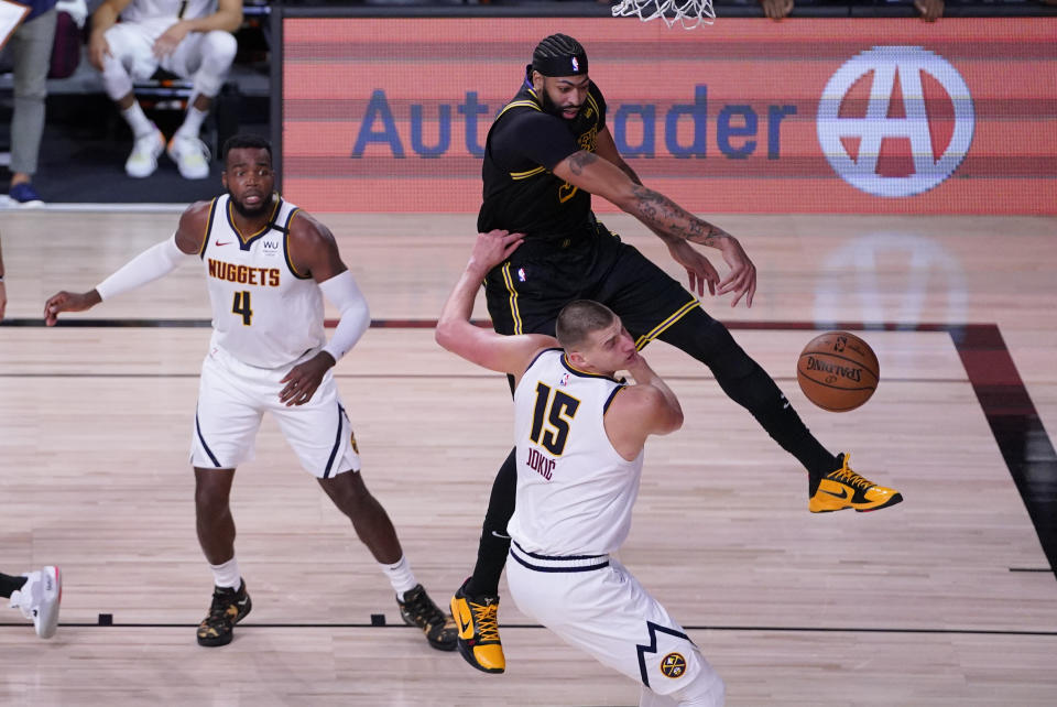 Los Angeles Lakers' Anthony Davis fights for a loose ball with Denver Nuggets' Nikola Jokic (15) and Paul Millsap (4) during the second half of an NBA conference final playoff basketball game Sunday, Sept. 20, 2020, in Lake Buena Vista, Fla. The Lakers won 105-103. (AP Photo/Mark J. Terrill)