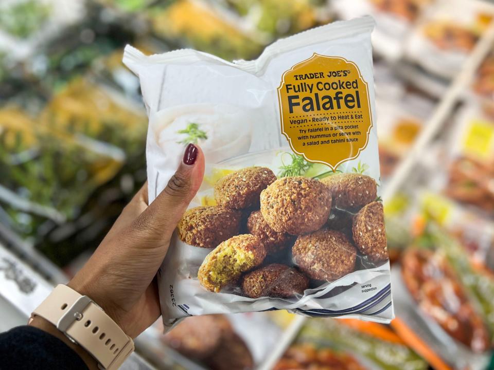 A hand holding a bag of Trader Joe's fully-cooked falafel.