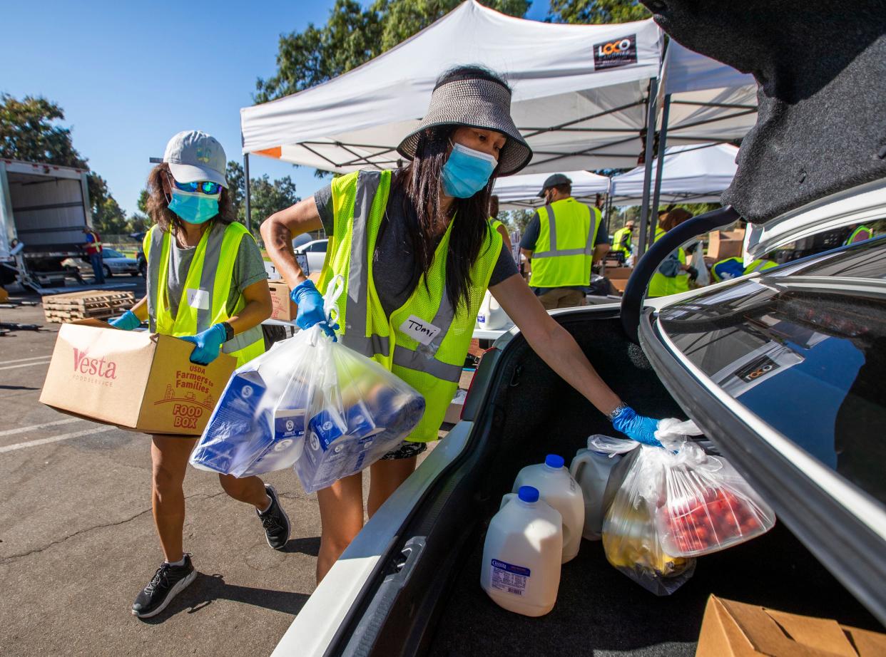 Volunteer Anh Tonnu (left) and sister Tomi Tonnu load a car in Fountain Valley, California, with food on Oct. 14 as part of Saddleback Church's drive-thru food distributions to families in need. (Photo: Allen J. Schaben/Los Angeles Times via Getty Images)