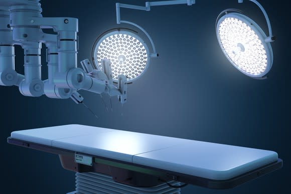Robotic surgery setup with an operating table and bright lights.