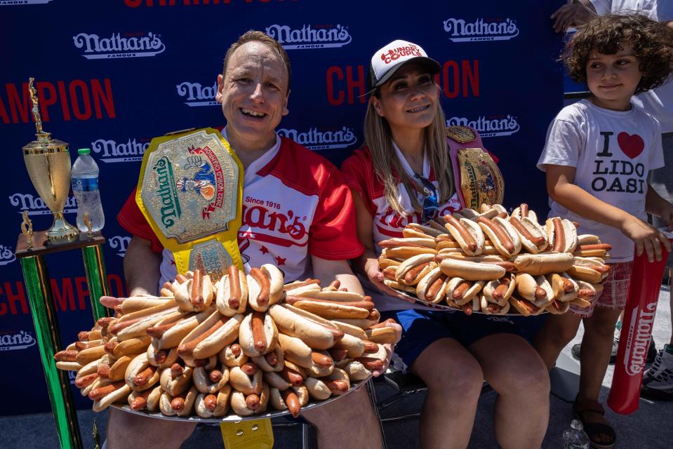 Joey Chestnut (L) and Miki Sudo (R) hold 63 and 40 hot dogs respectively after winning the Nathan's Famous 4th of July 2022 hot dog eating contest on Coney Island on July 4, 2022 in New York. (Photo by Yuki IWAMURA / AFP) (Photo by YUKI IWAMURA/AFP via Getty Images)