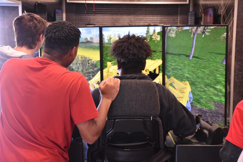 Gallatin High School students gather around an excavator simulator.