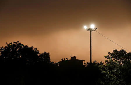 People stand on the roof of a house during a dust storm in New Delhi, India May 13, 2018. REUTERS/Adnan Abidi