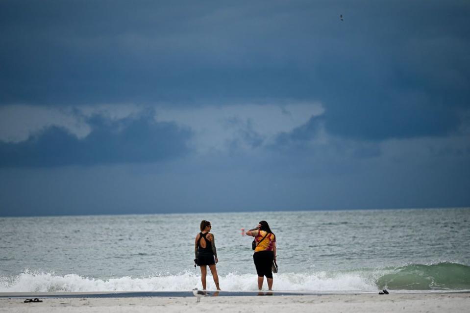 People enjoy the beach in the Tampa Bay area on Tuesday as dark clouds gather.