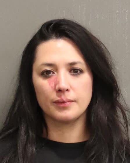 A mug shot of a woman with long hair showing a bruise below her right eye
