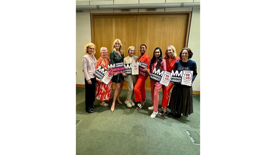 Penny Lancaster in patterned mini dress in line up of women holding signs