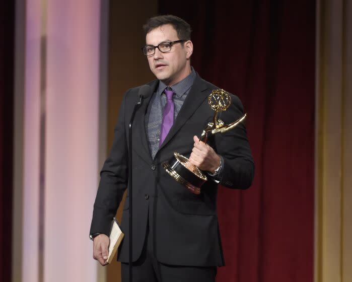 Tyler Christopher accepts a Daytime Emmy Award on stage while wearing glasses and a dark suit