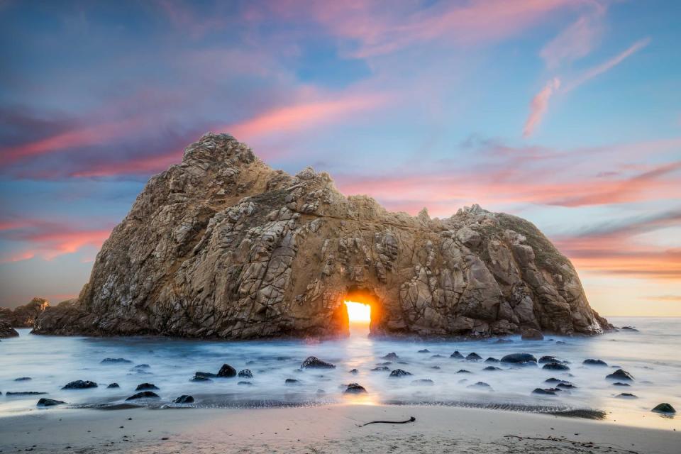 <p>The glowing sun appears in the "keyhole" of the Pfeiffer Beach rock in Big Sur, California.</p>