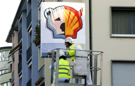 Members of Greenpeace put a banner over the company logo at a Shell gas station during a protest in Zurich, June 30, 2015. REUTERS/Arnd Wiegmann