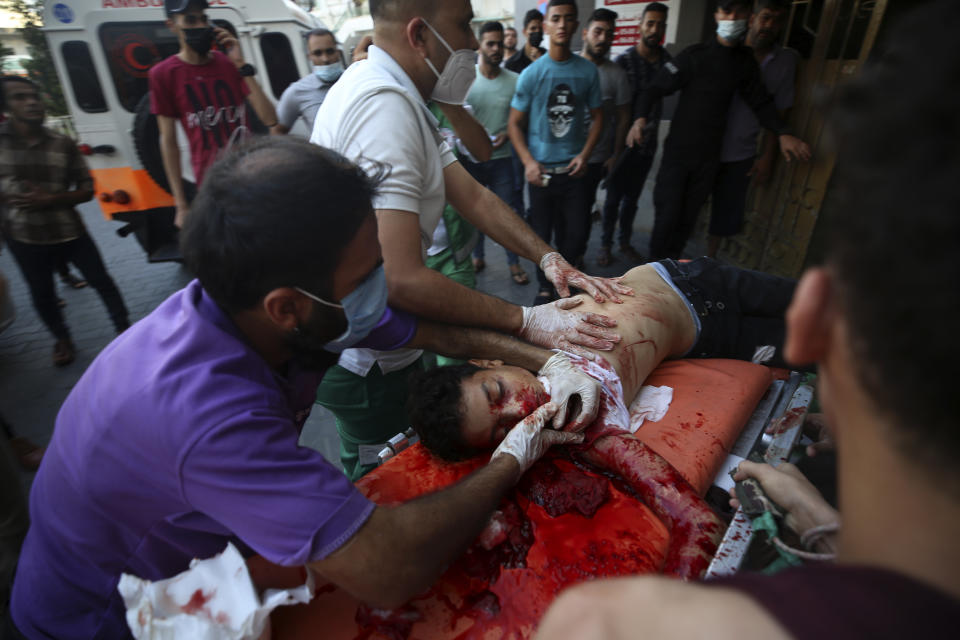 Medics and protestors move a wounded 13-year-old boy, who was shot by Israeli troops in his head during a protest at the Gaza Strip's border with Israel, into the treatment room of Shifa hospital in Gaza City, Saturday, Aug. 21, 2021. (AP Photo/Abdel Kareem Hana)