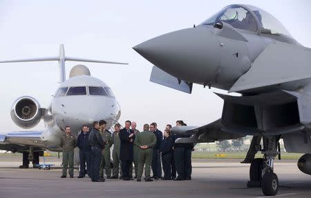 Prime Minister David Cameron (C) speaks with military personnel as he stands between an RAF Sentinel surveillance aircraft (L) and an RAF Eurofighter Typhoon fighter jet during his visit to Royal Air Force station RAF Northolt in London, Britain November 23, 2015. REUTERS/Justin Tallis/pool