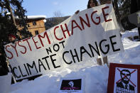 Demonstrators hold a banner during a protest outside the annual meeting of the World Economic Forum in Davos, Switzerland, Thursday, Jan. 24, 2019. On the ground are posters with pictures of Bazilian President Jair Bolsonaro. (AP Photo/Markus Schreiber)