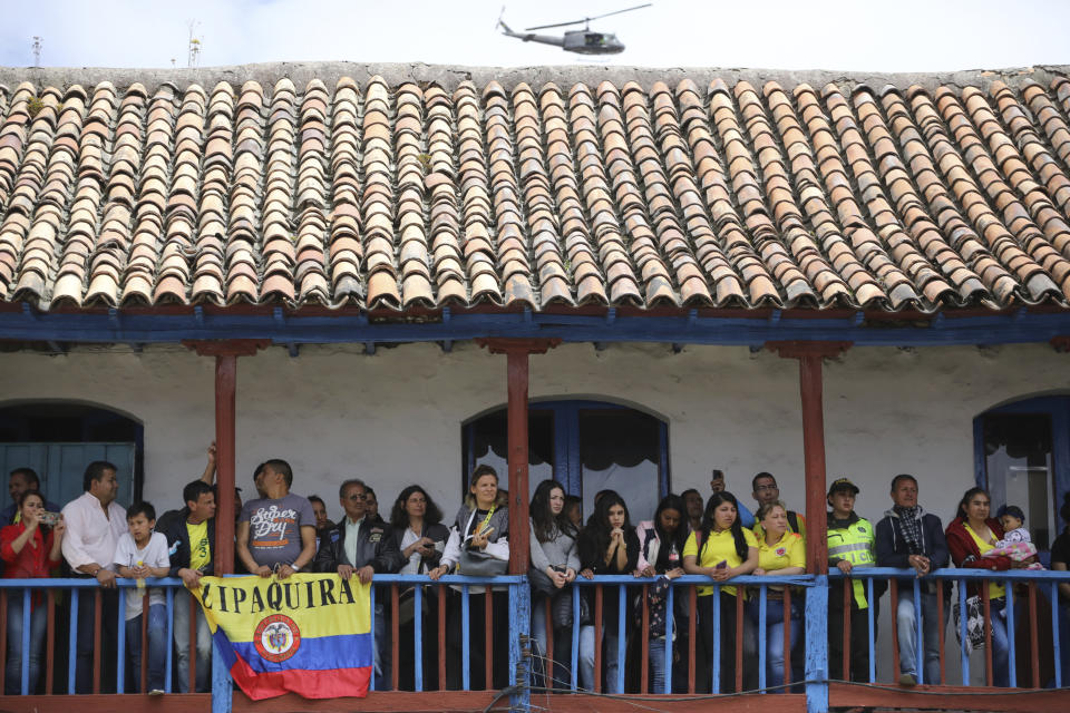 Locals look from a balcony as Tour de France winner Egan Bernal arrives to Zipaquira, Colombia, Wednesday, Aug. 7, 2019. Bernal rode into the town's central square on his bike on wearing the Tour de France's iconic yellow jersey. A group of some 3,000 supporters dressed in the same color chanted his name. (AP Photo/Ivan Valencia)