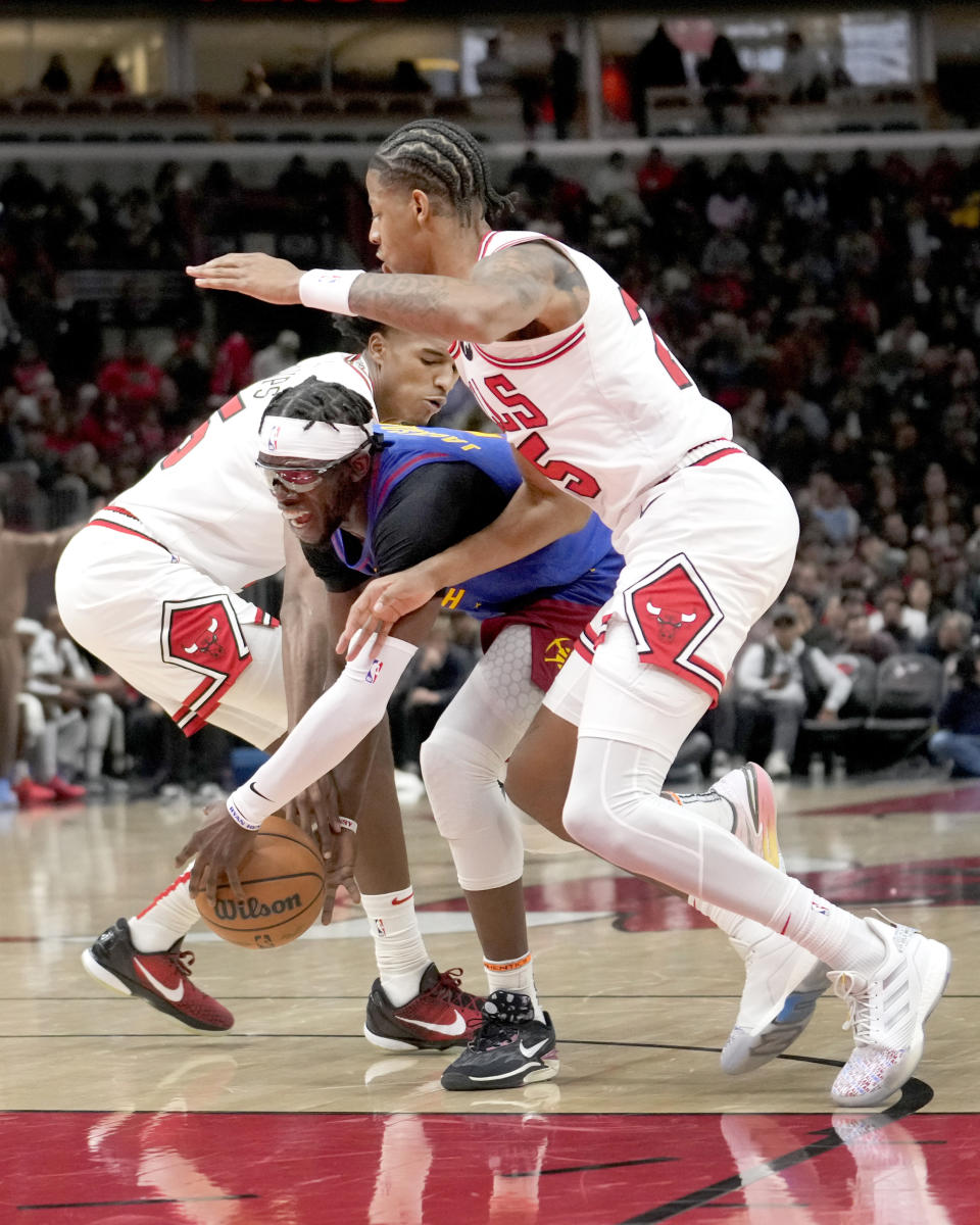 Denver Nuggets guard Reggie Jackson, center, drives to the basket between Denver Nuggets center Nikola Jokic, left, and Dalen Terry during the first half of an NBA basketball game Tuesday, Dec. 12, 2023, in Chicago. (AP Photo/Charles Rex Arbogast)