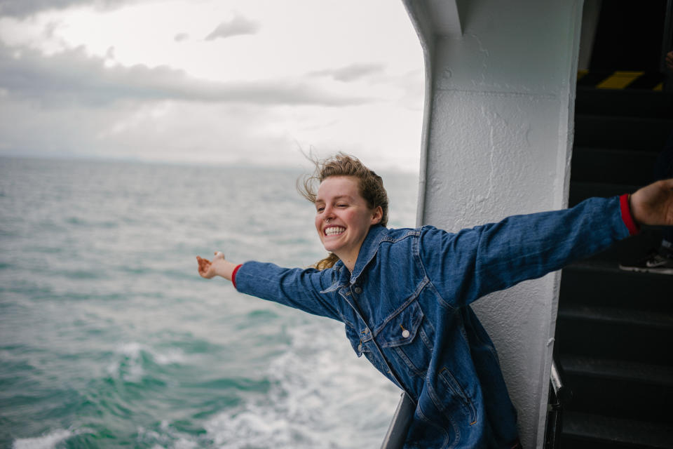 A woman on a boat is grinning and enjoying the water