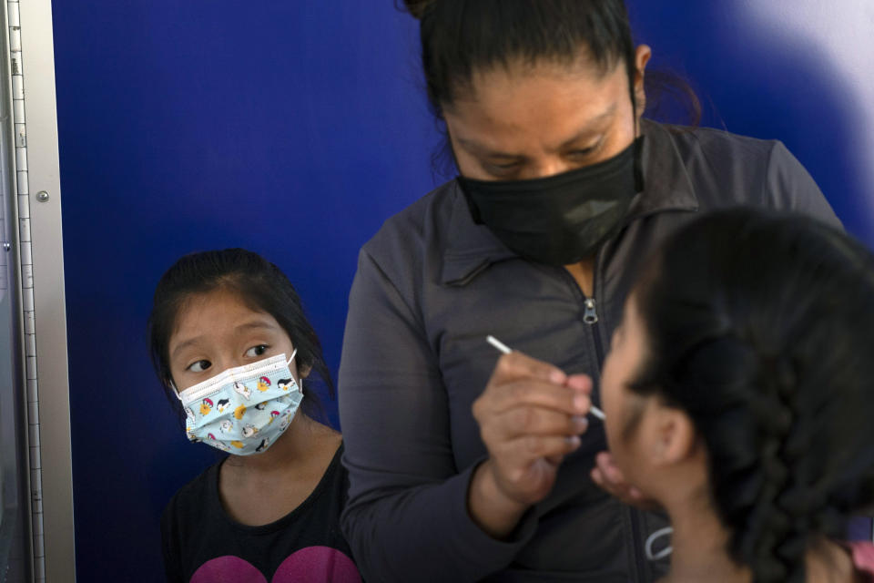 FILE - In this Dec. 9, 2020, file photo, Katie Ramirez, left, watches as her mother, Claudia Campos, swabs the mouth of her daughter, Hailey, for a COVID-19 test at a testing site in Los Angeles. As officials met to discuss approval of a COVID-19 vaccine on Thursday, Dec. 10, the number of coronavirus deaths has grown bleaker than ever. (AP Photo/Jae C. Hong, File)