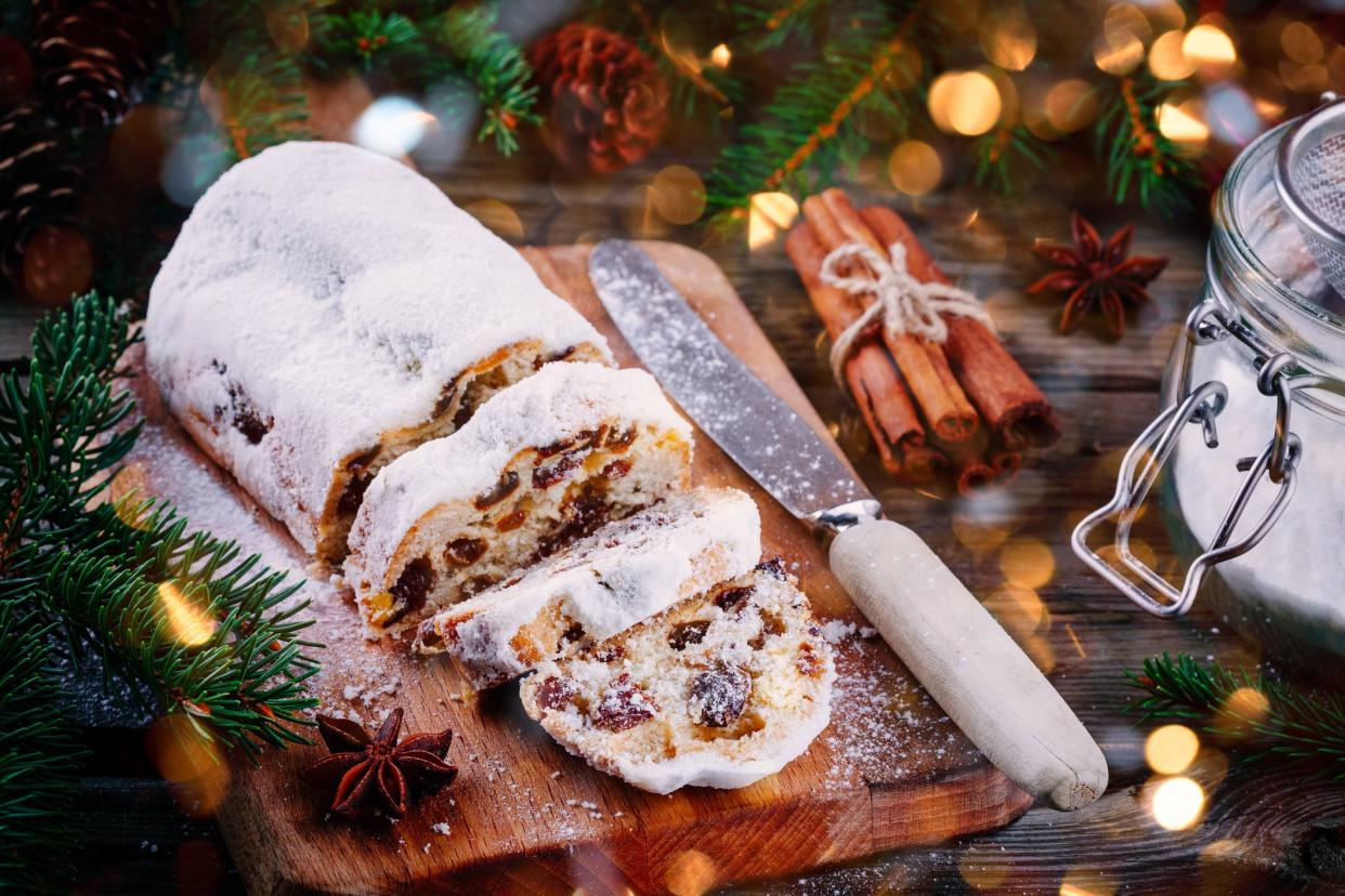 Traditional Christmas Stollen Fruit Cake on wooden rustic background with Christmas Lights