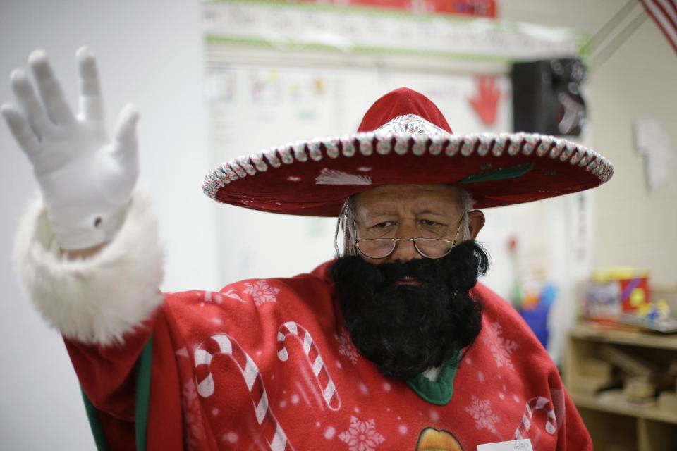 In this Friday, Dec. 20, 2013, photo, Pancho Claus, Rudy Martinez, waves to children as he visits Knowlton Elementary School, in San Antonio. Pancho Claus, a Tex-Mex Santa borne from the Chicano civil rights movement in the late 1970s and early 1980s, is now an adored Christmas fixture in many Texas cities. (AP Photo/Eric Gay)