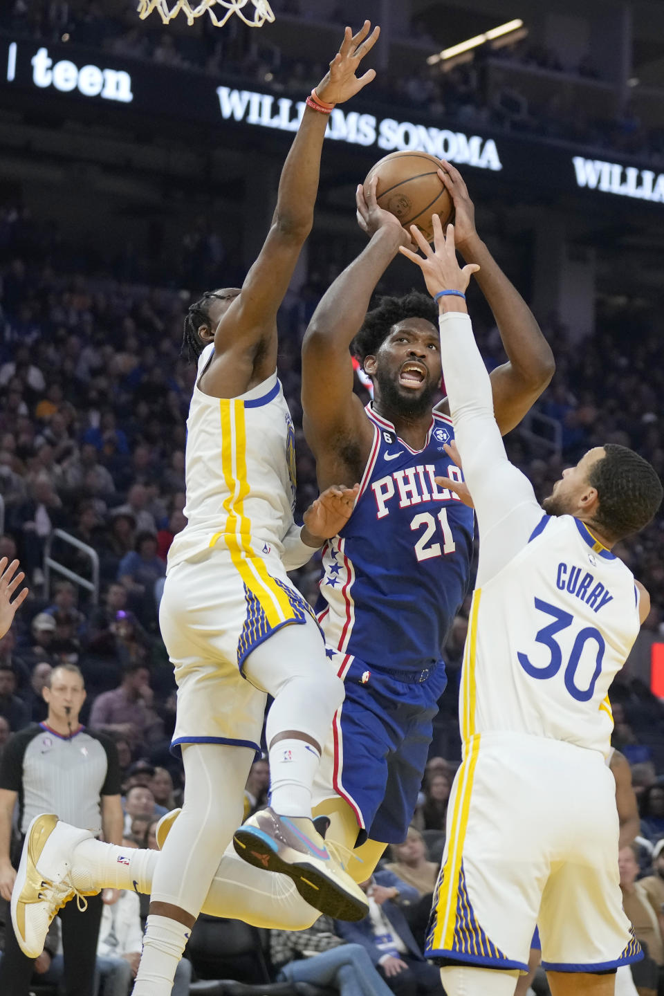 Philadelphia 76ers center Joel Embiid (21) shoots between Golden State Warriors forward Jonathan Kuminga, left, and guard Stephen Curry (30) during the first half of an NBA basketball game in San Francisco, Friday, March 24, 2023. (AP Photo/Jeff Chiu)