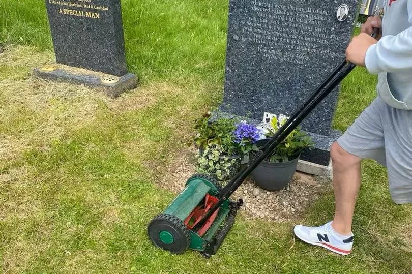 Lawnmower in front of Alan Michael Turner's grave at Carlton Cemetery, Carlton, Nottinghamshire, after grass has been cut, being pushed by man in grey goodie, grey shorts and New Balance trainers