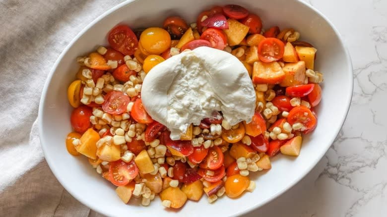 Tomato peach burrata salad in white bowl