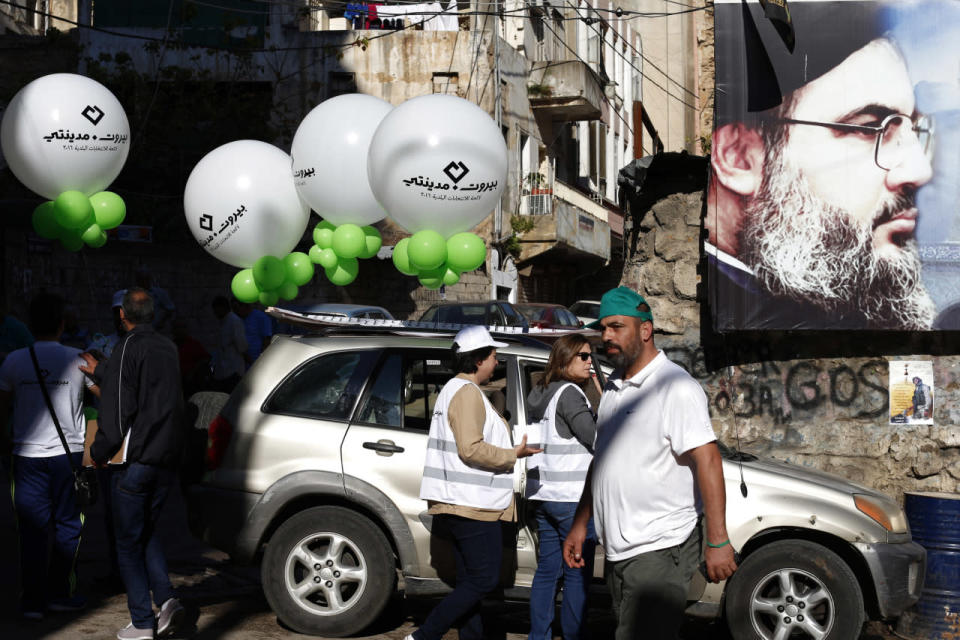 Beirut Madinati campaign workers hold balloons next to a poster showing Hezbollah leader Hassan Nasrallah , outside a polling station during the municipal elections in Beirut, Lebanon, May 8, 2016. (Hassan Ammar/AP)