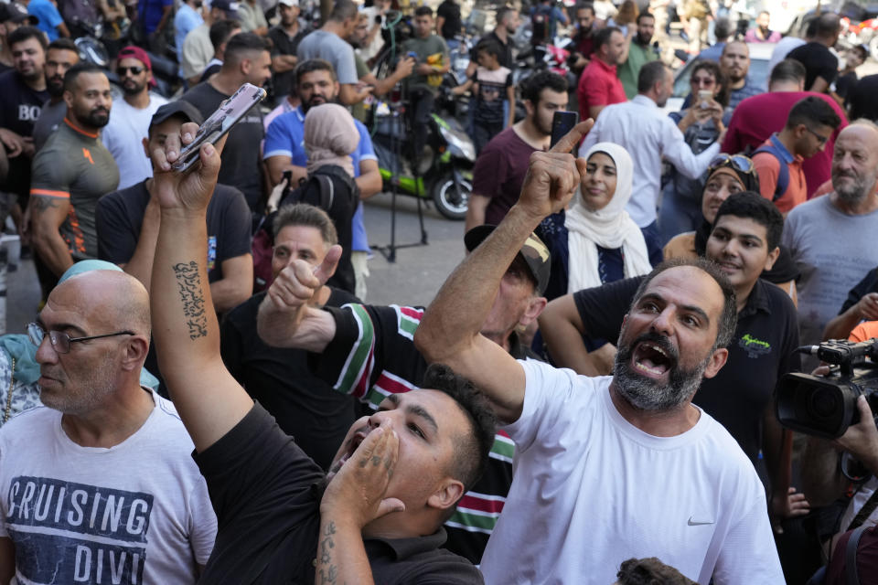 People shout slogans against the Lebanese banks outside of a BLOM bank branch where a man who is identified as Abed Soubra, is allegedly holding hostages in an effort to get to funds in his account in Beirut, Lebanon, Friday, Sept. 16, 2022. Depositors broke into at least four banks in different parts of crisis-hit Lebanon Friday demanding that they get their trapped savings as chaos spreads in the small Mediterranean nation in the middle of a historic economic meltdown. (AP Photo/Bilal Hussein)