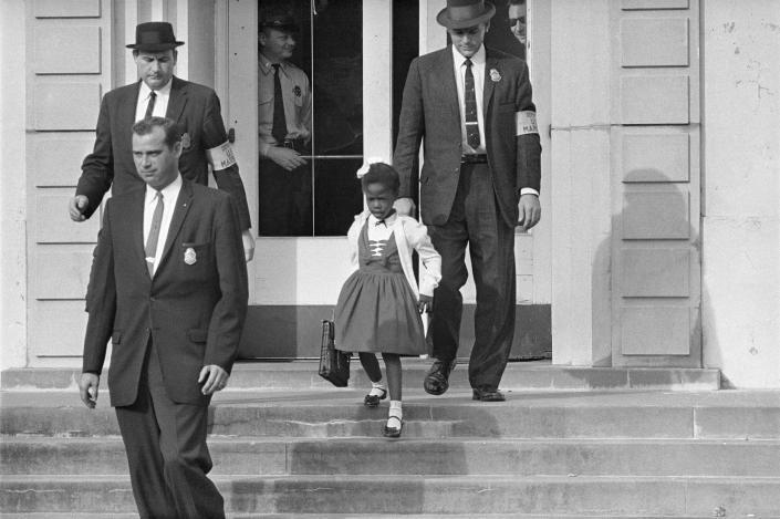 معاون مارشال های ایالات متحده، روبی بریجز 6 ساله را از مدرسه ابتدایی ویلیام فرانتز در نیواورلئان، در این عکس فایل نوامبر 1960 اسکورت می کنند.  (عکس AP)