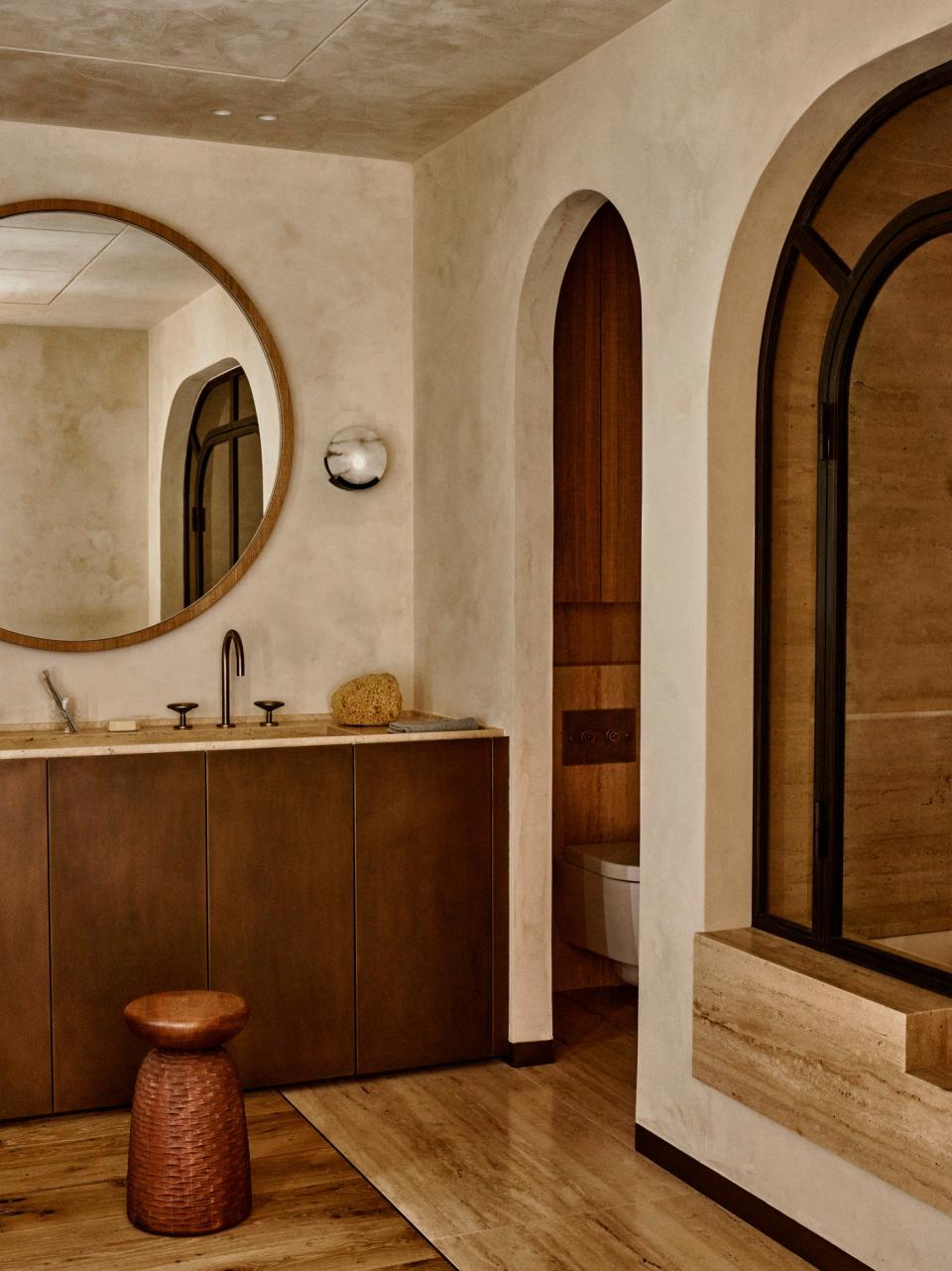 In the guest bathroom, sconces by Kelly Wearstler were included. Both the basin in travertine stone with oak bronze effect cupboards and the bath were made to measure. The faucet is from the Watermark Collection.