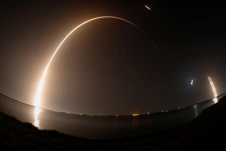 A SpaceX Falcon Heavy rocket, carrying the U.S. Air Force's Space Test Program 2 Mission, lifts off from the Kennedy Space Center in a time exposure that also shows the two booster rockets landing back at Cape Canaveral, Florida