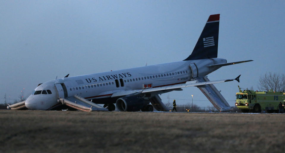 A damaged US Airways jet lies at the end of a runway at the Philadelphia International Airport, Thursday, March 13, 2014, in Philadelphia. Airline officials said the flight was heading to Fort Lauderdale, Fla., when the pilot was forced to abort takeoff around 6:30 p.m., after the front landing gear failed. An airport spokeswoman said no injuries have been reported. (AP Photo/Matt Slocum)