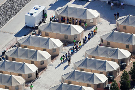 FILE PHOTO: Immigrant children now housed in a tent encampment under the new "zero tolerance" policy by the Trump administration are shown walking in single file at the facility near the Mexican border in Tornillo, Texas, U.S. June 19, 2018. REUTERS/Mike Blake/File Photo