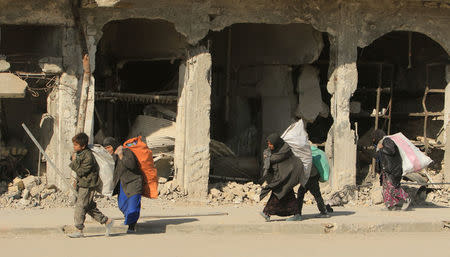 FILE PHOTO - Iraqi people carry bags in Mosul, Iraq, January 10, 2018. REUTERS/Ari Jalal