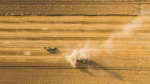 <p>A combine harvester makes its way across an orange field, pictured from directly above. </p>