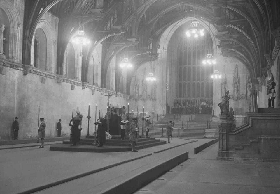 ARCHIVO – El fallecido rey Jorge VI recibe honores de Estado de cuerpo presente en el Salón Westminster en Londres el 11 de febrero de 1952. Isabel II recibe honores de Estado de cuerpo presente en el Salón Westminster en el Palacio de Westminster en Londres el miércoles 14 de septiembre de 2022. Los restos de la reina permanecerán en el salón hasta horas antes de su funeral de Estado el lunes. Se espera que acudan cientos de miles de personas a despedirse. (Foto AP/Rider)