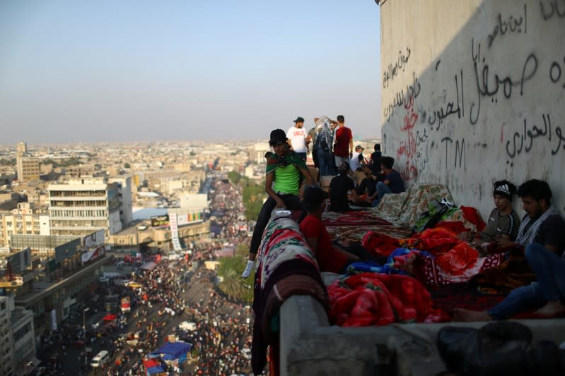 Iraqi demonstrators are seen on the top of the high-rise building, called by Iraqi the Turkish Restaurant Building, during anti-government protests in Baghdad