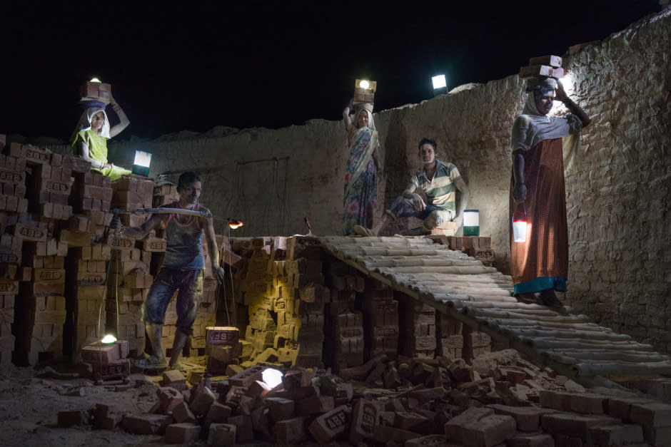 Workers use solar lamps to collect newly baked bricks at night to be arranged in Amit Brickfield, Saipur, India, on June 5, 2015.