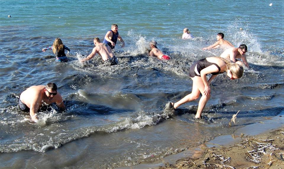 Participants in the inaugural Dave and Friends Polar Bear Plunge splash in the frigid waters of Lake Farmington on Jan. 1, 2022.