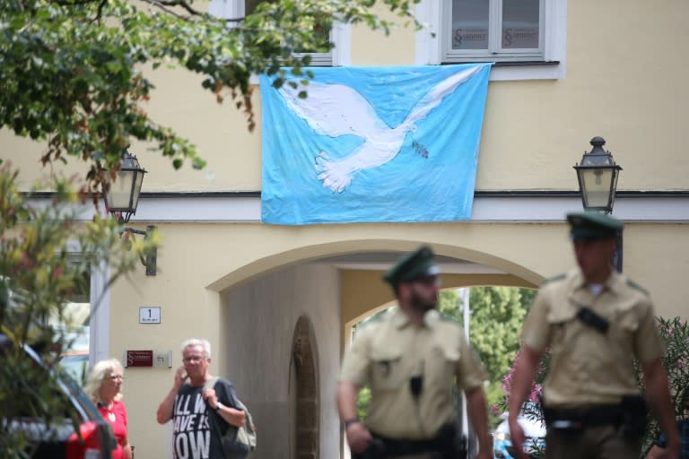 Policemen pass by a banner depicting a peace dove in the centre of Ansbach, southern Germany, at the site of the July 26, 2016 attack