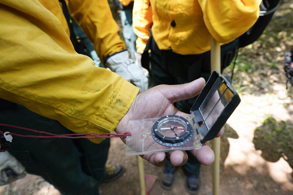 An instructor demonstrates how to use a compass to students during a wildland firefighter training Friday, June 9, 2023, in Hazel Green, Ala. A partnership between the U.S. Forest Service and four historically Black colleges and universities is opening the eyes of students of color who had never pictured themselves as fighting forest fires. (AP Photo/George Walker IV)